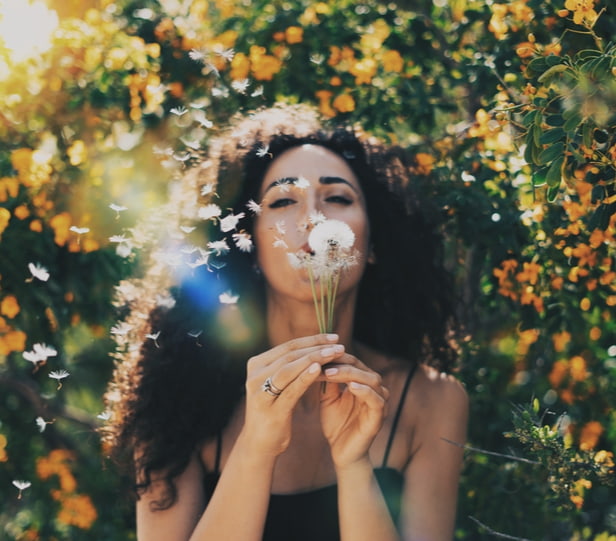 happy woman blowing a dandelion